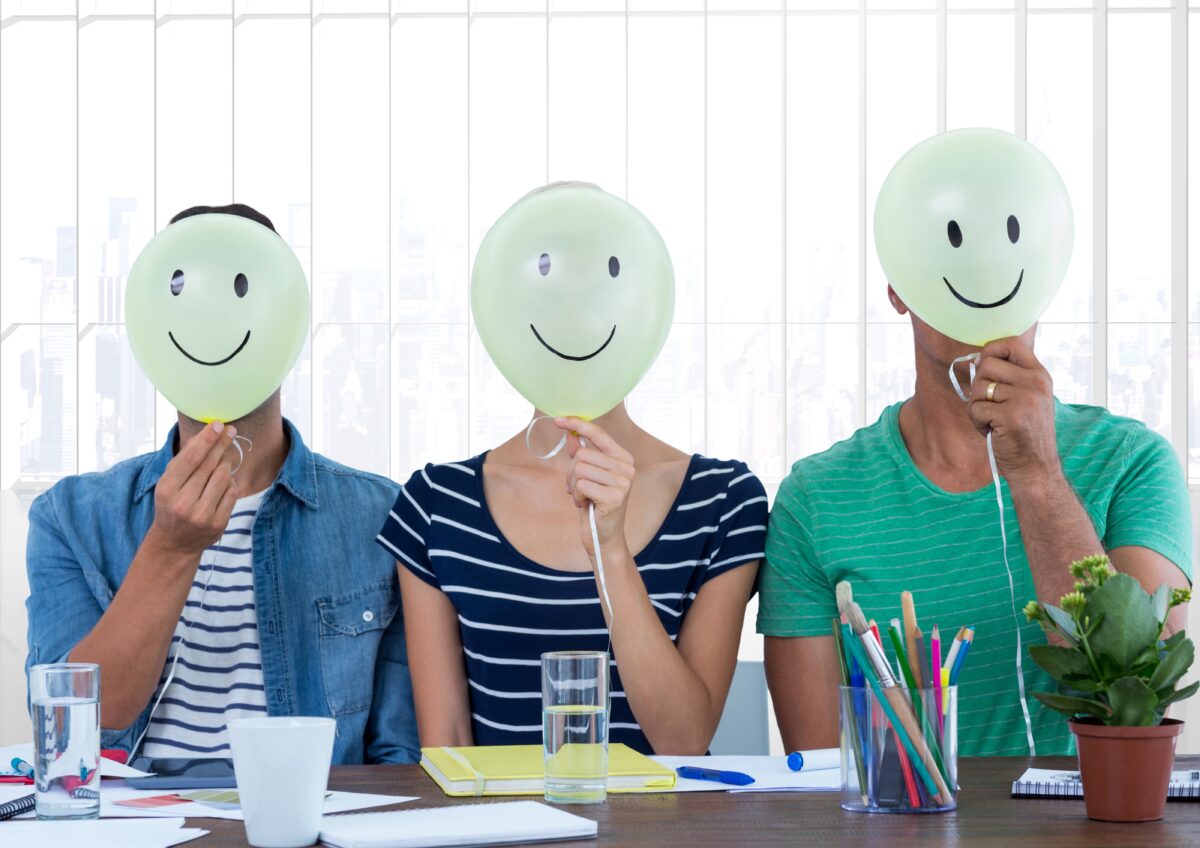 Colleagues holding smiley while sitting on desk at office This guide will help you become a Positive Behaviour Support Practitioner in Australia