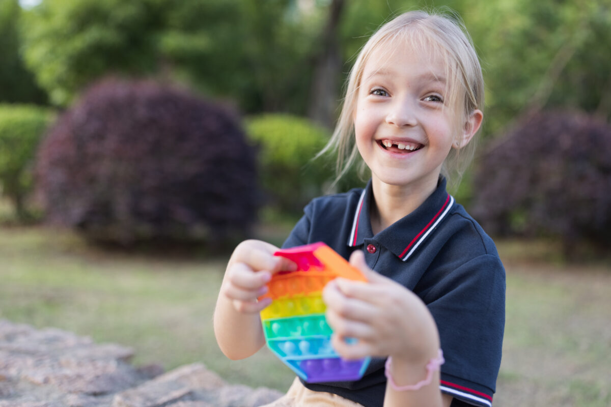 little caucasian girl is playing with new trendy pop it toy. Development of fine motor skills, Push bubble fidget sensory toy – washable and reusable silicon stress relief toy. Anti stress toy for children with special needs. Mental health concept Global Developmental Delay vs Autism: Understanding the Differences